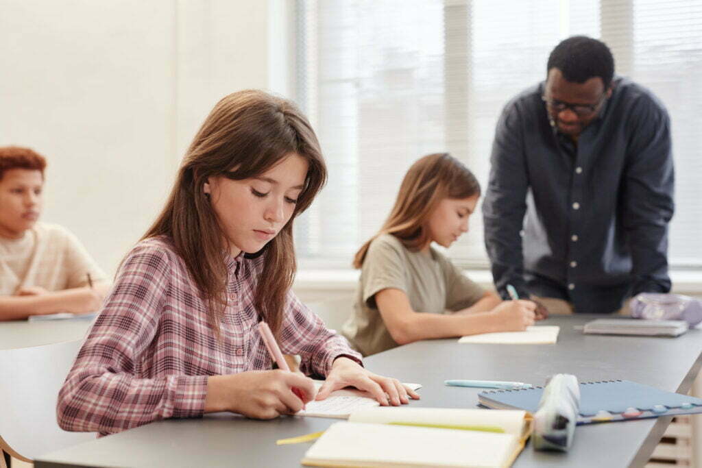 Student taking notes in classroom, illustrating tips for doing well in school.
