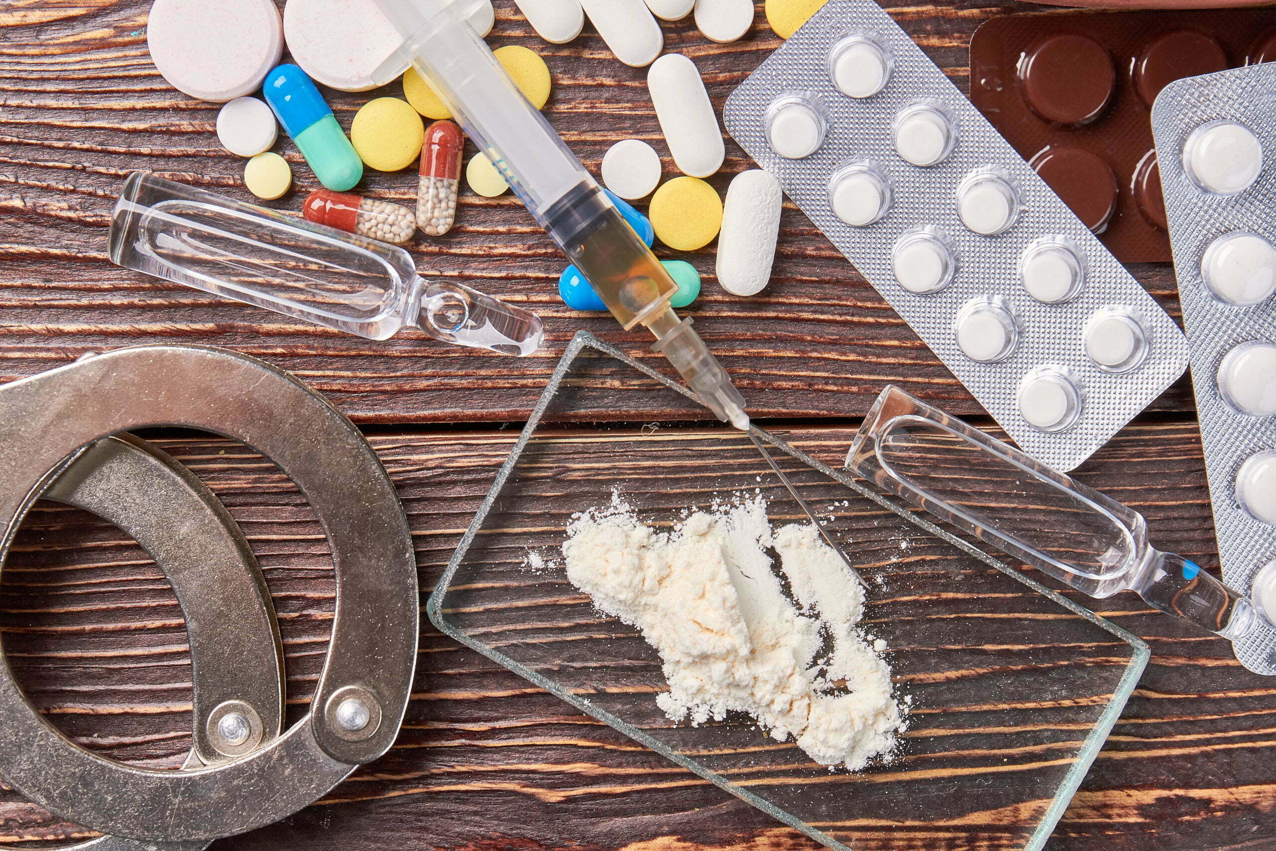 Drug addiction paraphernalia and handcuffs illustrating the challenges of overcoming addiction.