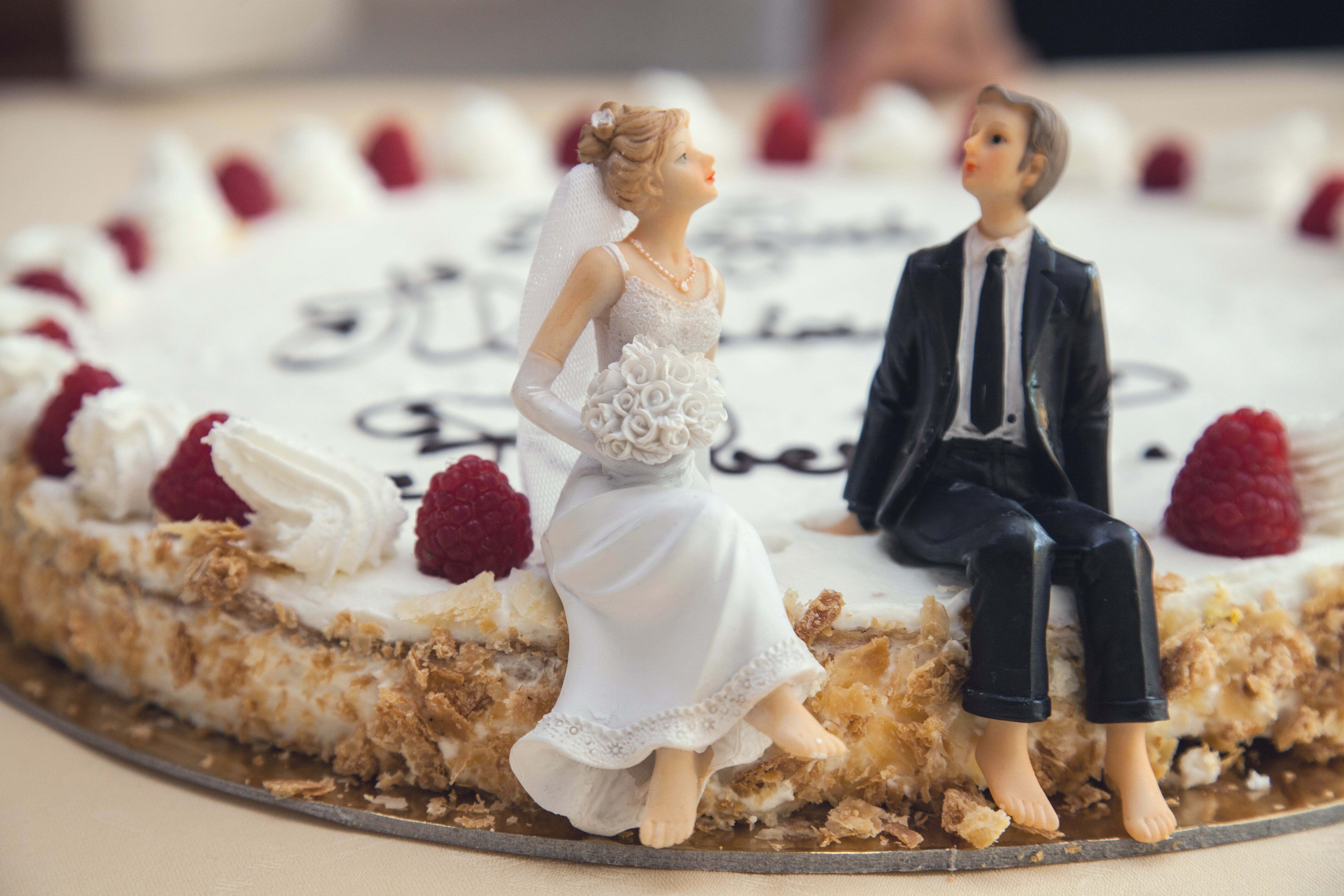 a man and woman standing next to a cake