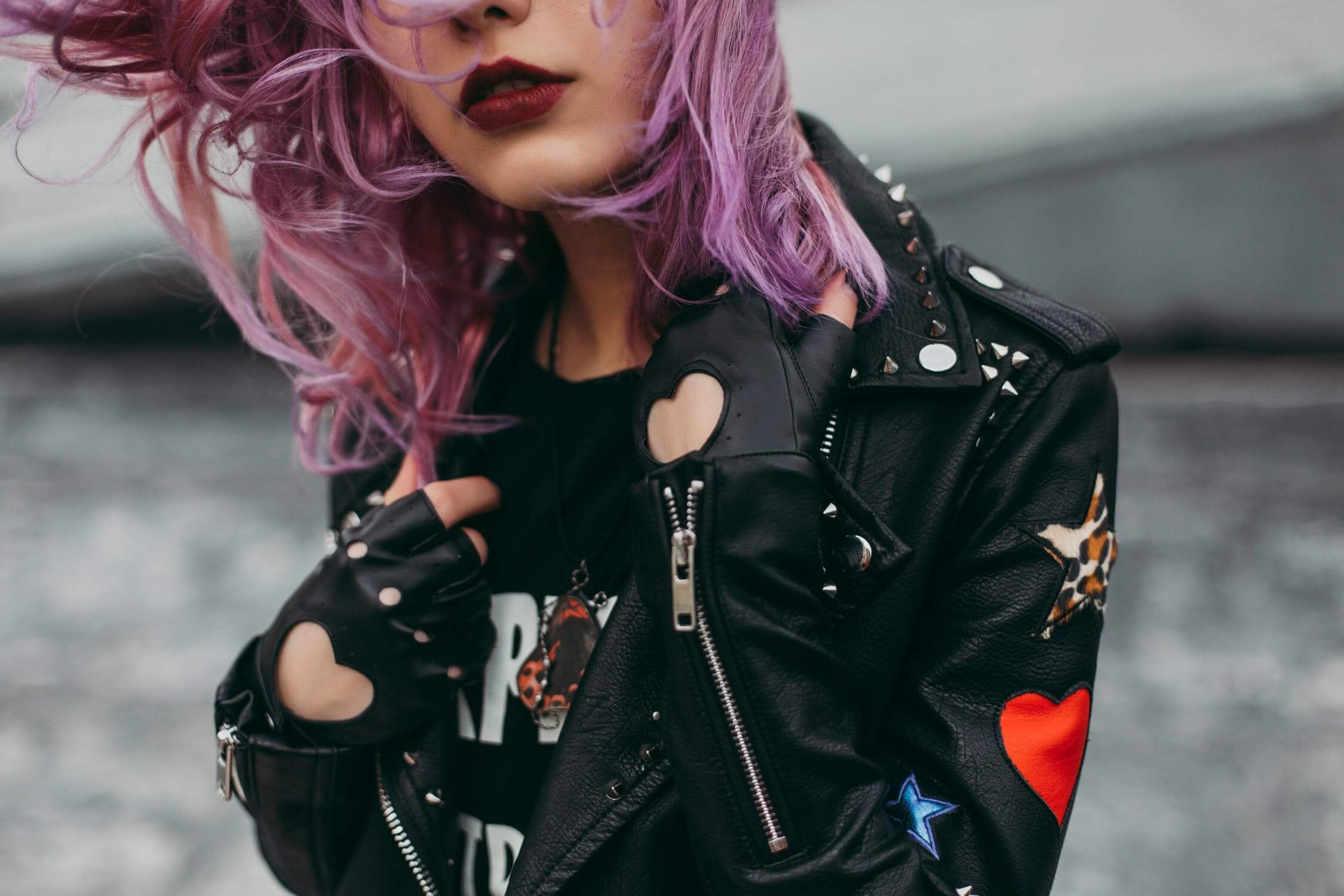a woman wearing a black jacket and pink hair