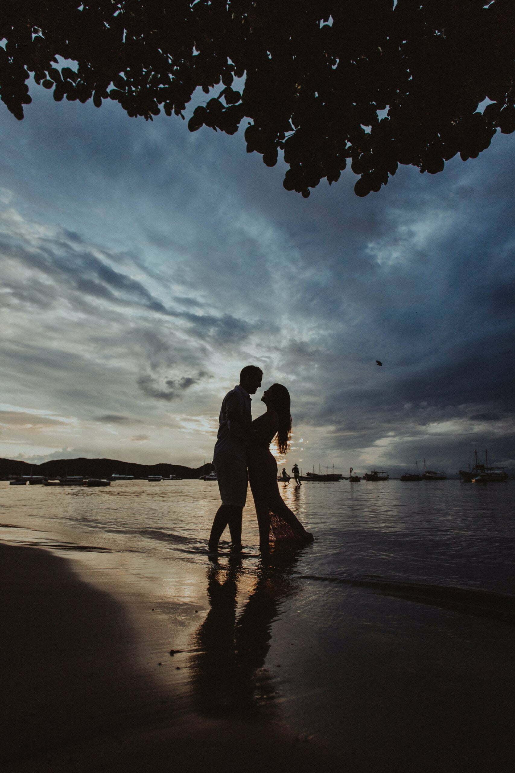 a man and woman kissing on a beach