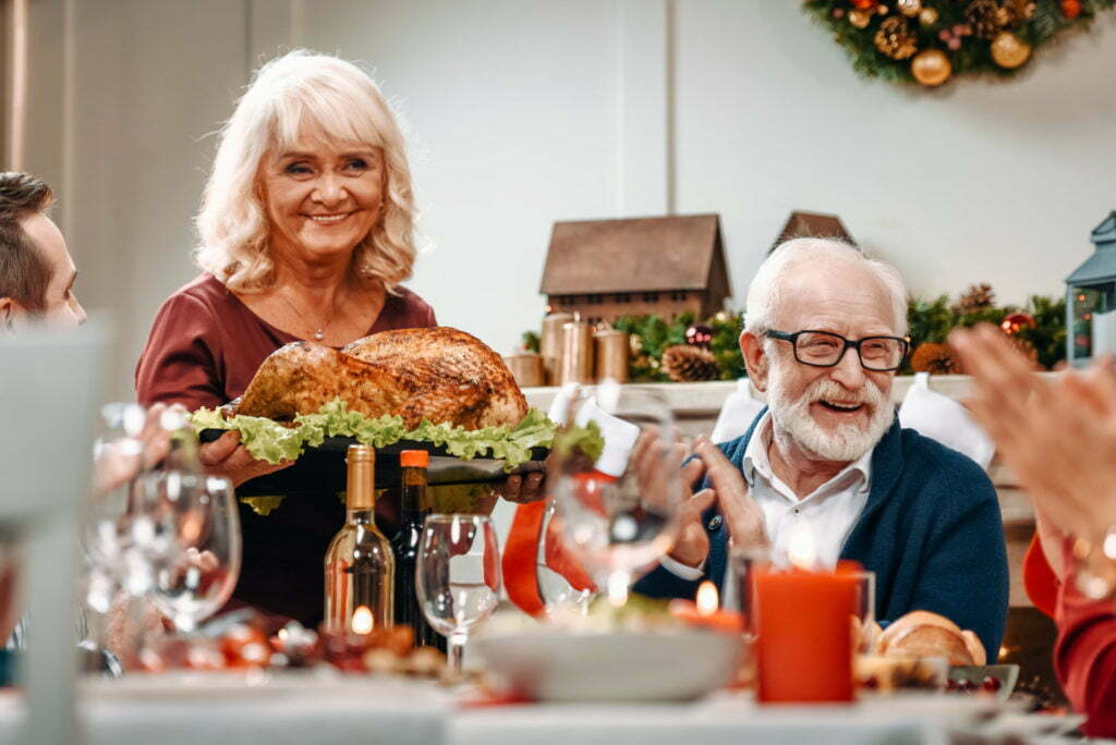 senior couple at christmas table with delicious turkey for family