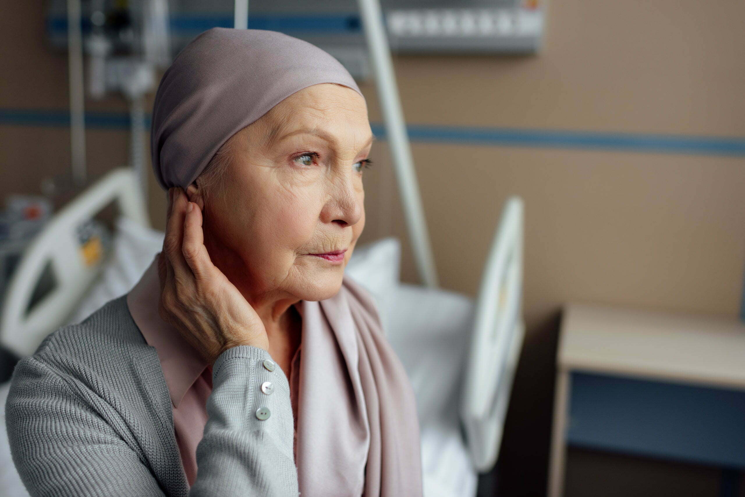 upset senior woman with cancer sitting on bed in hospital