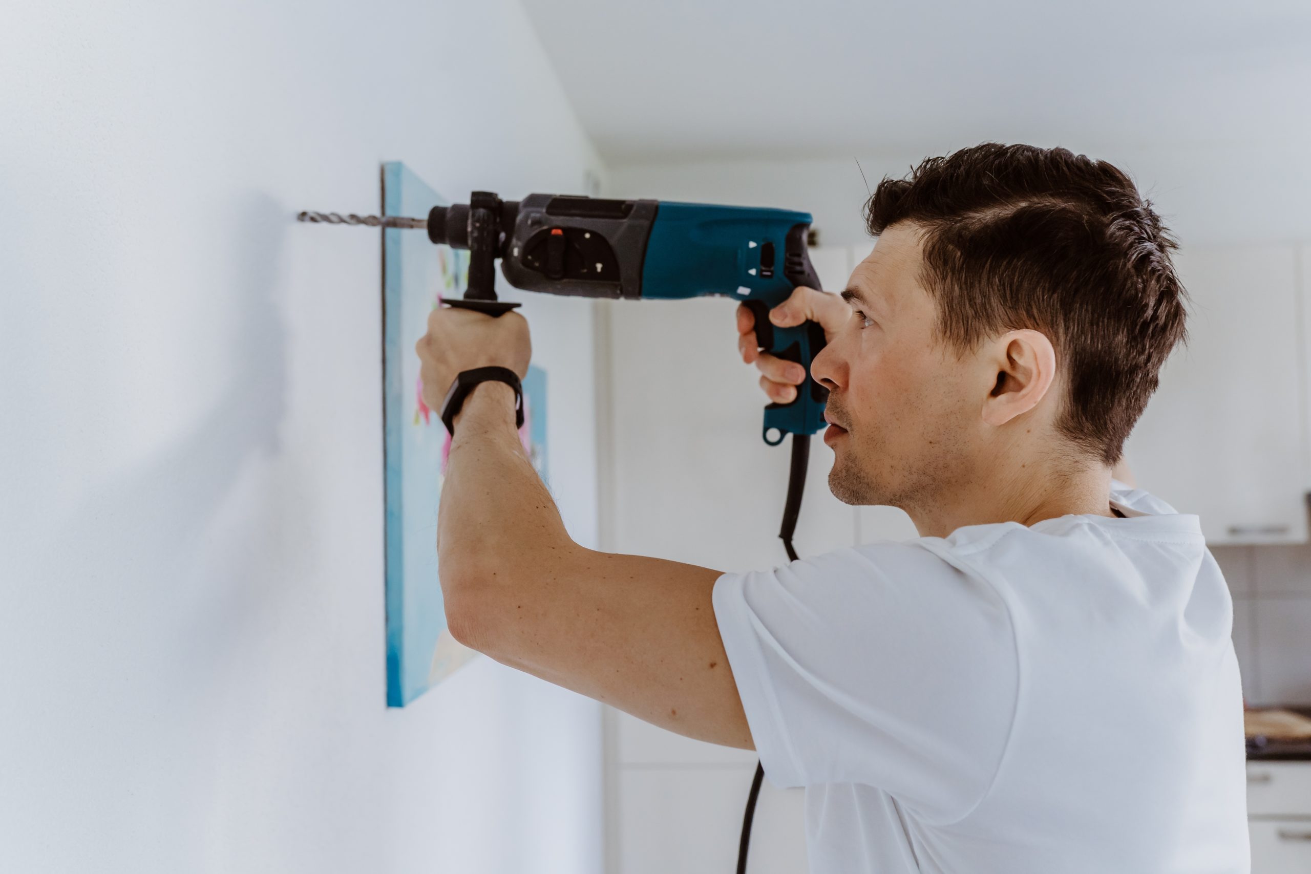 Husband for hour home repairing service. Portrait of handyman drilling a hole in wall